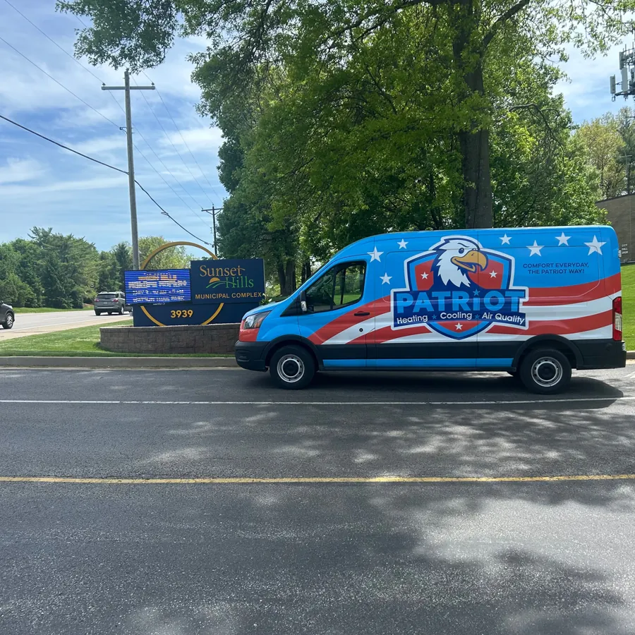 Patriot Heating, Cooling and Air Quality branded van parked beside the Sunset Hills Municipal Complex sign on a sunny day