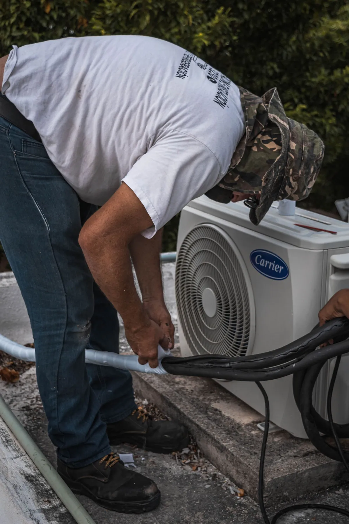 Technician clearing the lineset and coil on an outdoor air conditioning condenser