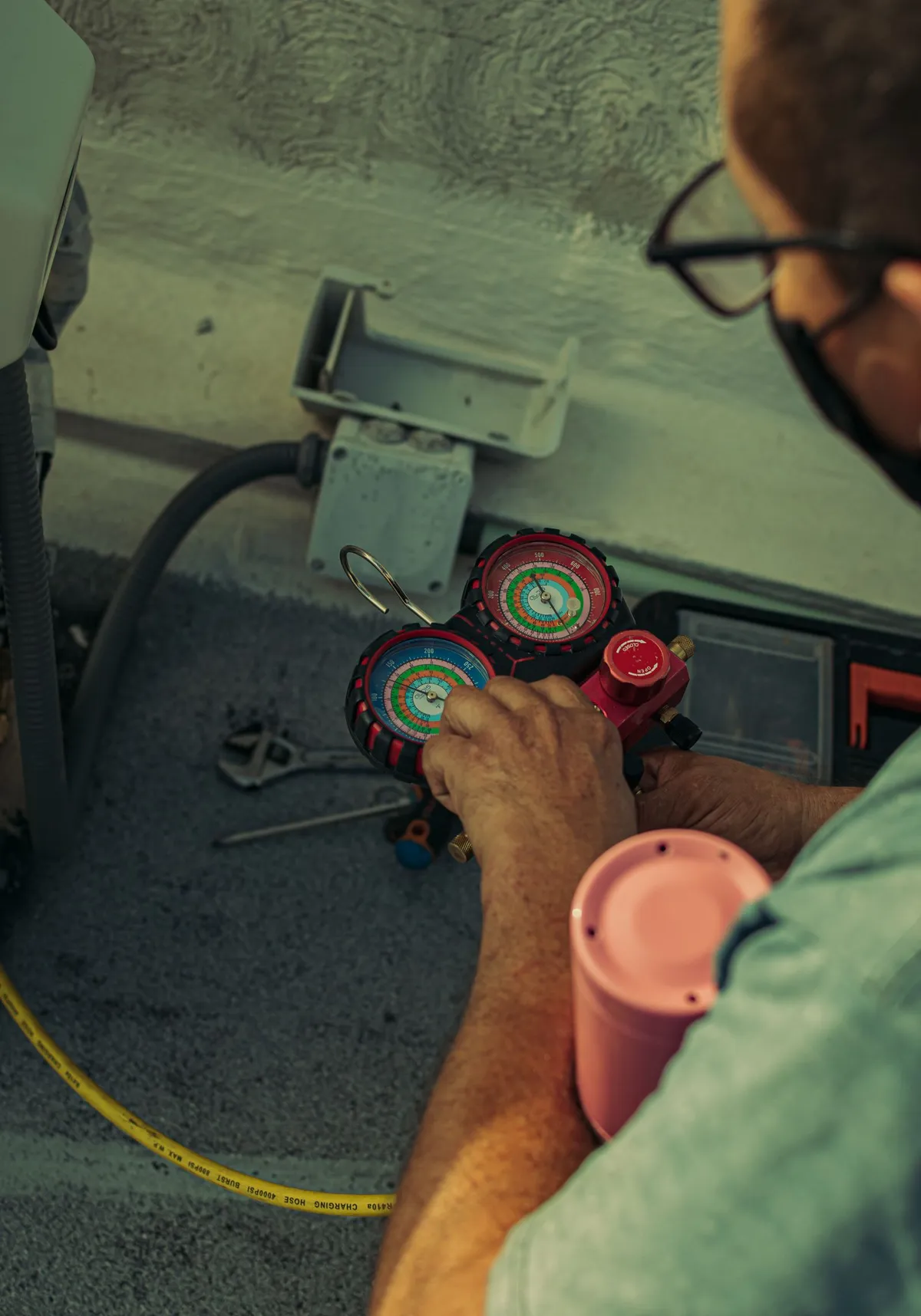 Technician holding refrigerant manifold gauges while servicing an air conditioning system