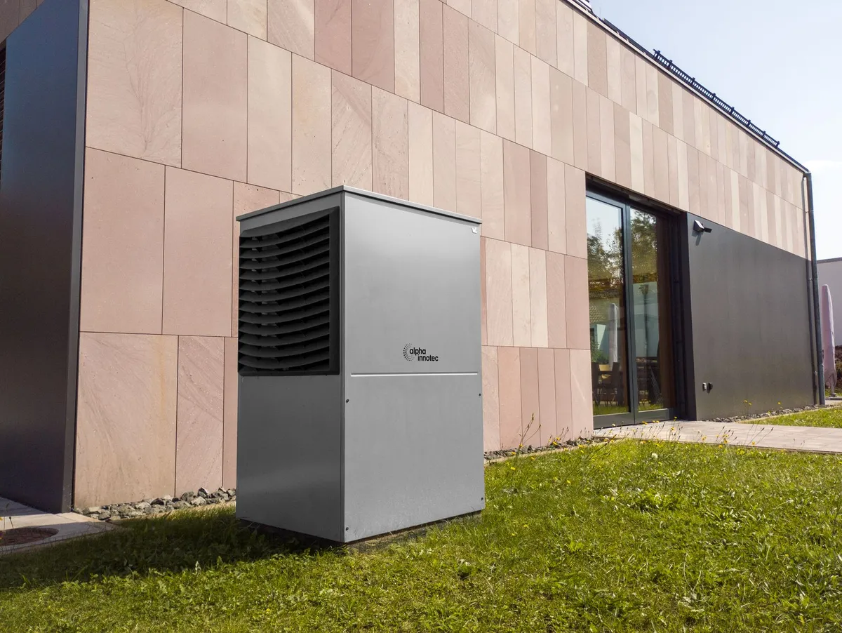 Heat pump unit installed on a gravel bed beside a modern building