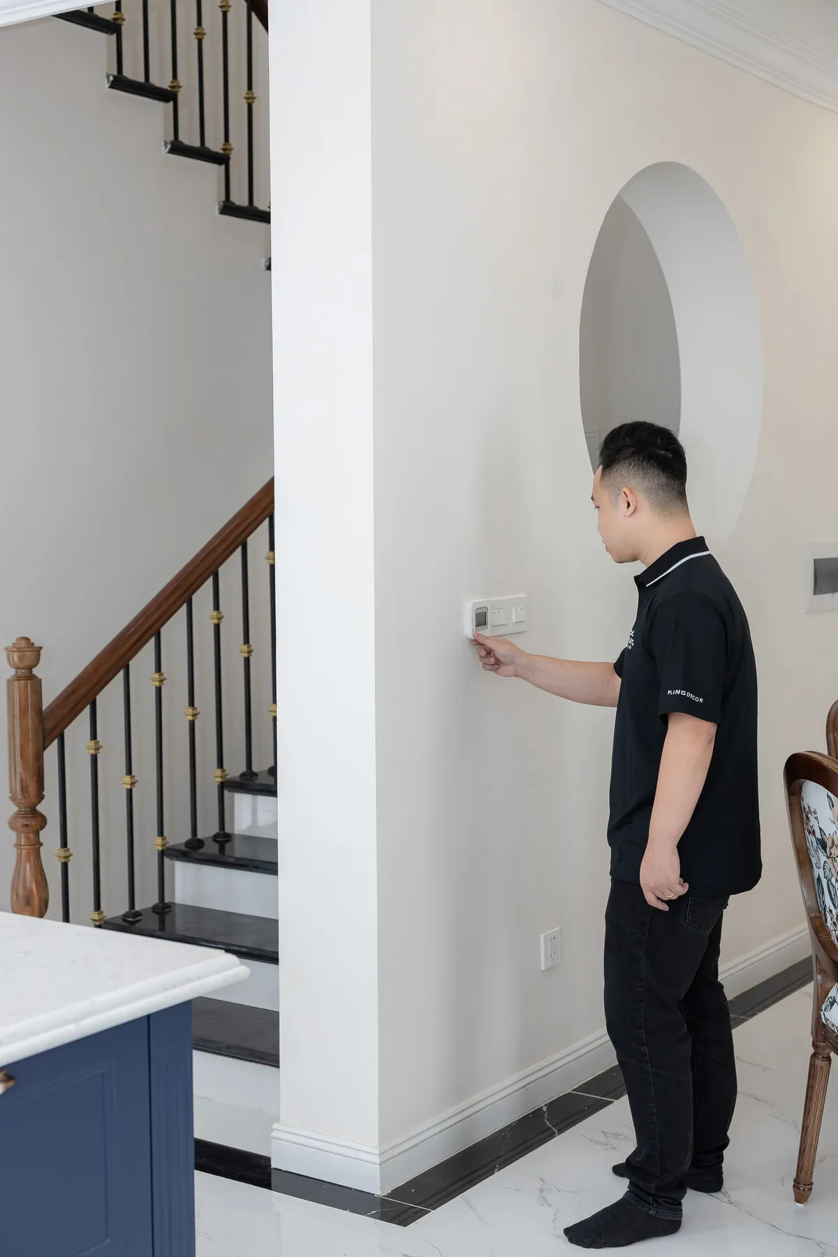 Man adjusting a wall thermostat in a home hallway